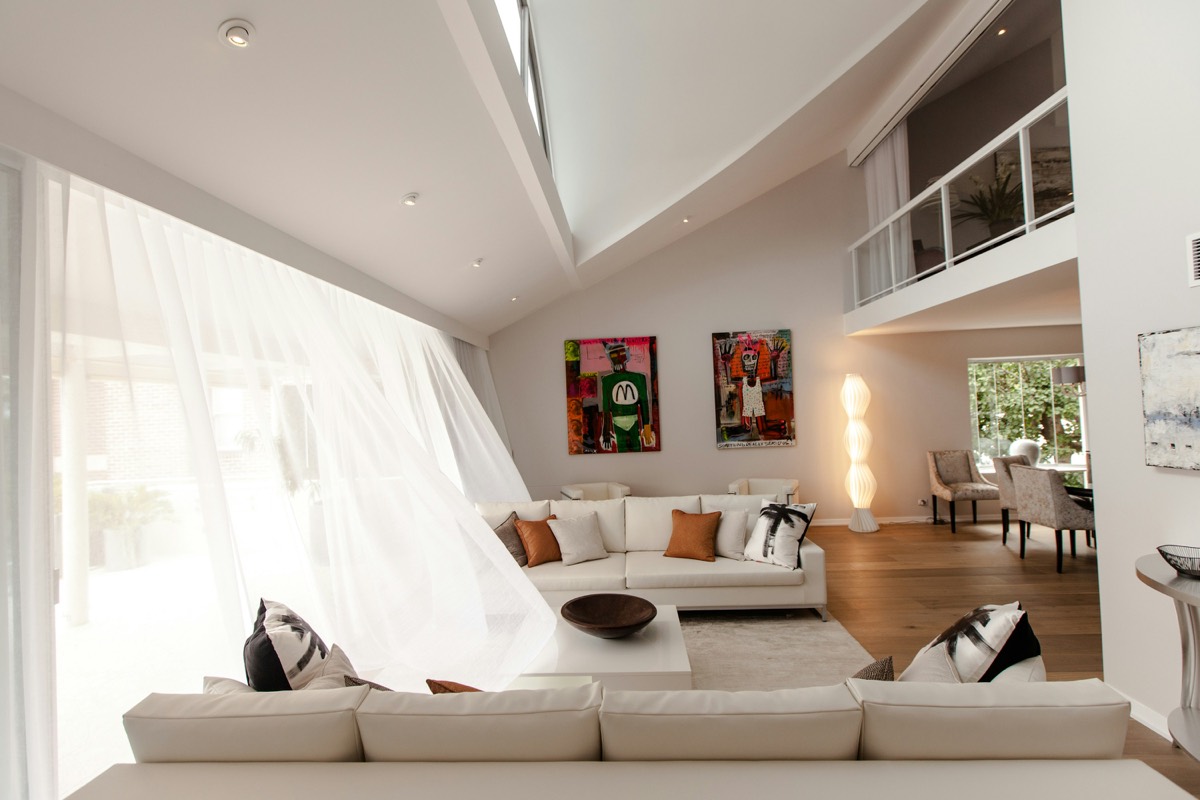 A light drawing room with a high void and art on the walls.